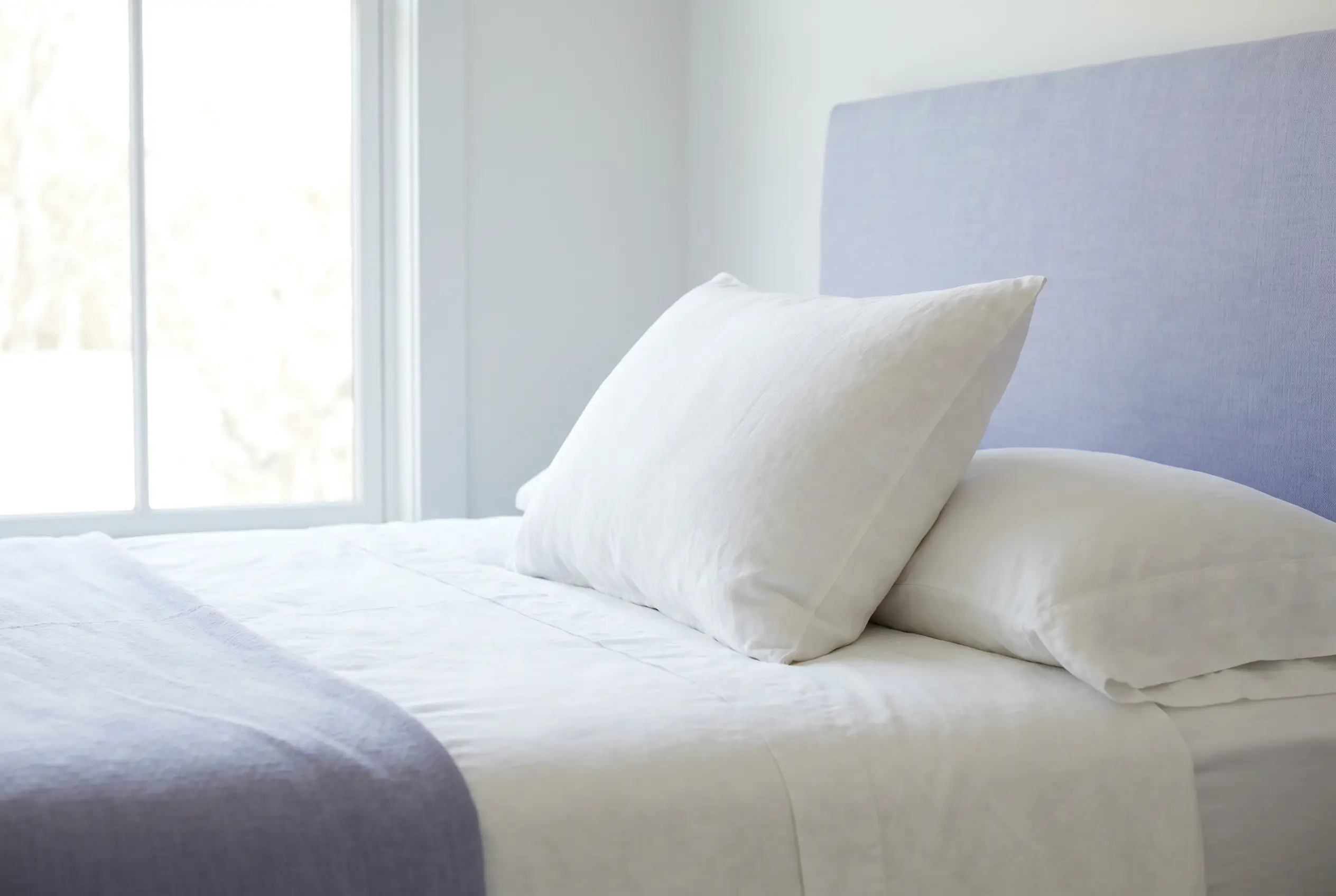 A medium-loft pillow shown from the side on a crisp white bed
