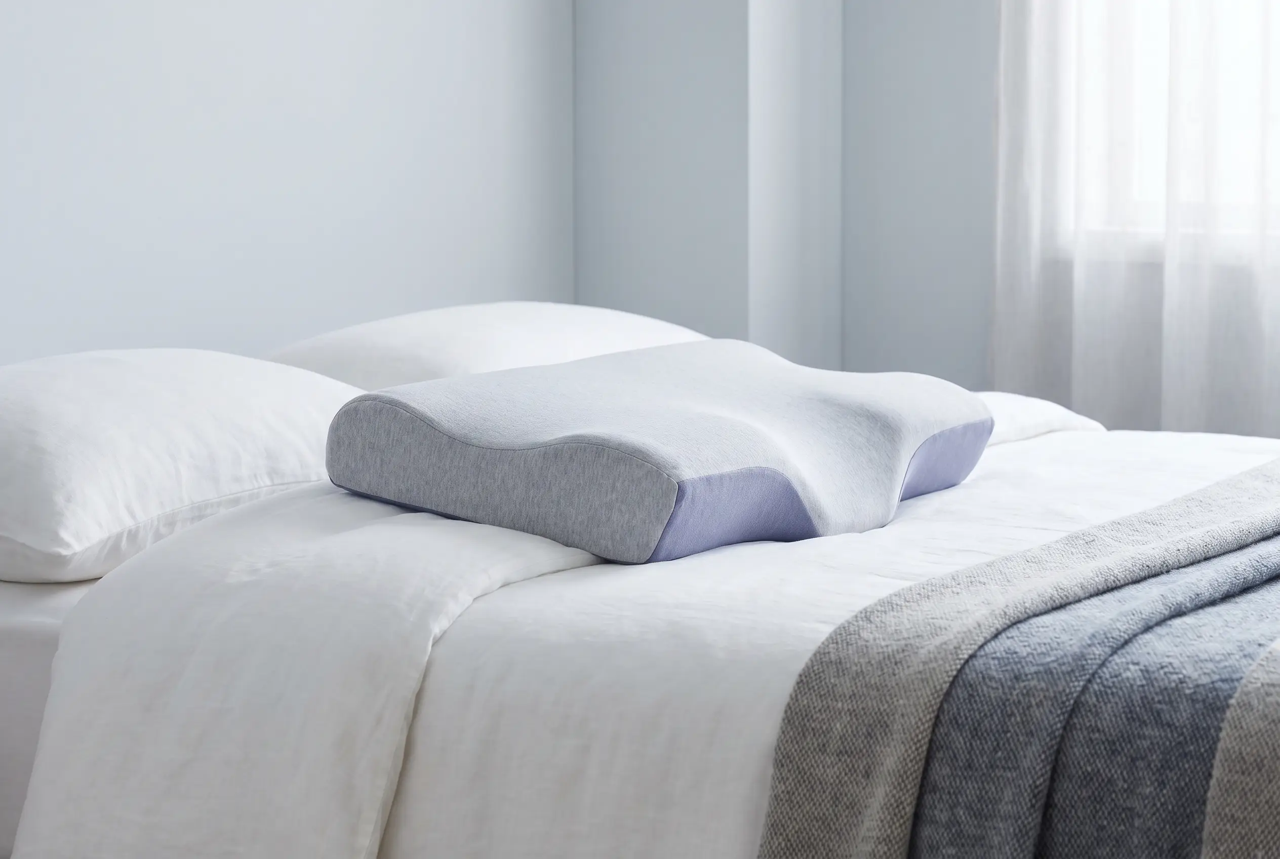 Side profile of a contour cervical pillow showing its curved neck-support shape